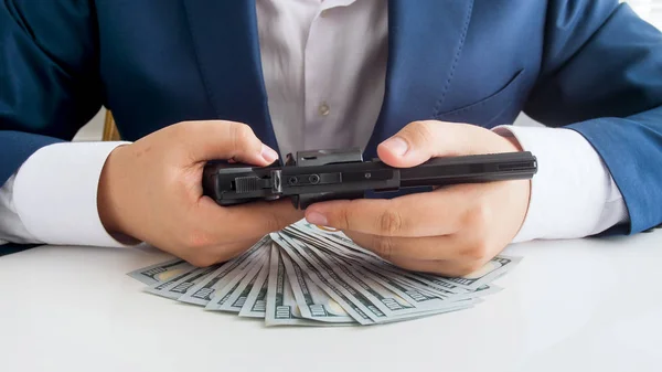 Closeup photo of businessman protecting his money with handgun — Stock Photo, Image