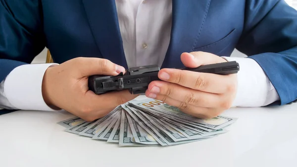Closeup photo of businessman in suit with lots of money holding revolver in hands — Stock Photo, Image