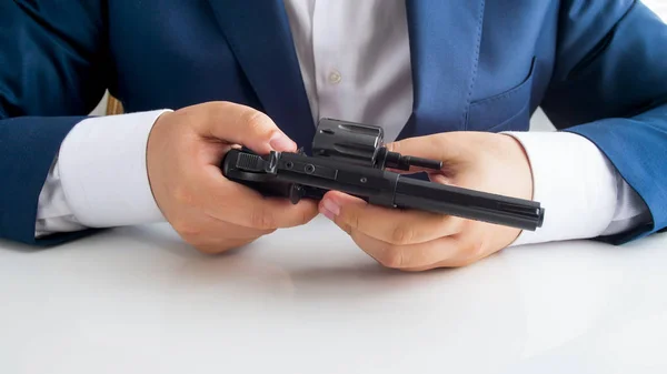Closeup image of businessman sitting in office and checking his personal handgun — Stock Photo, Image