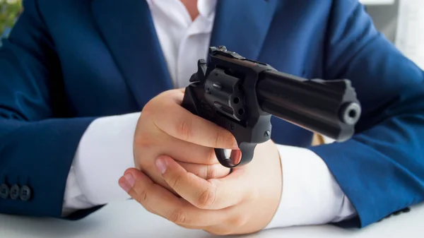 Closeup photo fo businessman in suit sitting in armchair and aiming with revolver — Stock Photo, Image