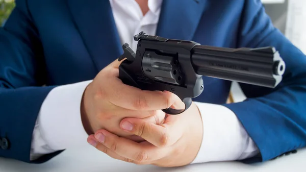 Closeup photo of businessman in suit sitting in office and holding revolver — Stock Photo, Image