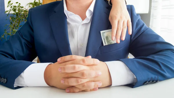 Closeup image of female hand taking money from businessmans pocket in office — Stock Photo, Image