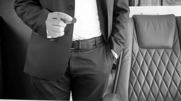 Fekete-fehér kép üzletember a kezében tartja a érme — Stock Fotó
