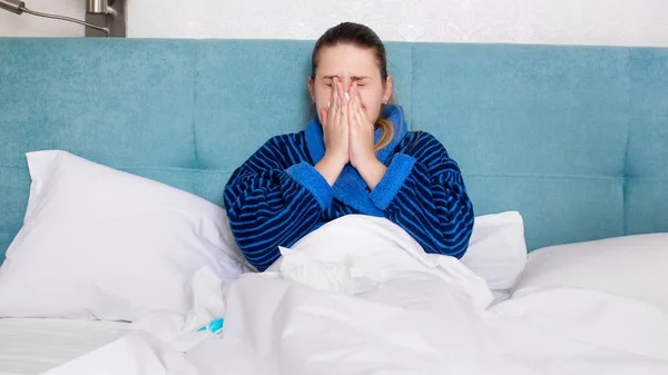 Portrét mladé ženy nemocné s rýma, ležící v posteli a blosing nos v tkáni — Stock fotografie