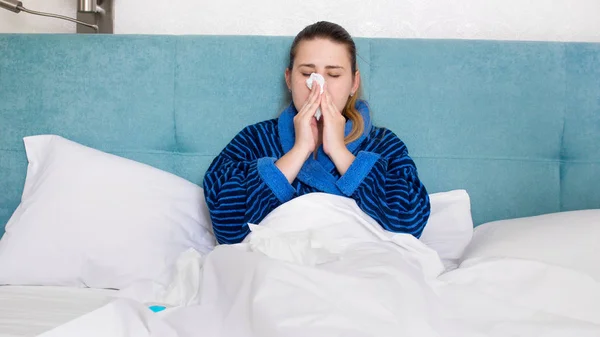 Retrato de una mujer joven con gripe sonándose la nariz en papel —  Fotos de Stock