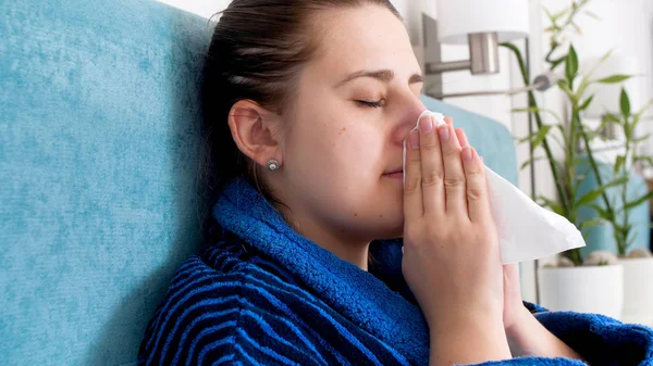Portret van zieke vrouw gevangen koude rusten op bed thuis en blazen neus in papieren zakdoek — Stockfoto