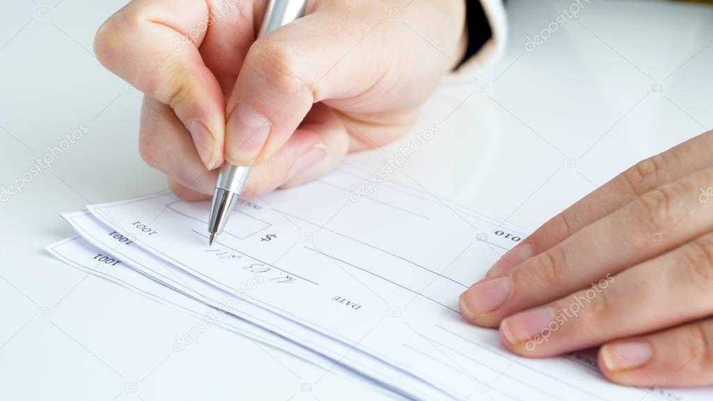 Closeup image of businesswoman signing banking cheque
