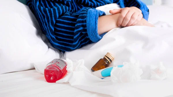 Imagen de primer plano de píldoras, dolor de garganta y aerosol nasal en la cama de la mujer enferma —  Fotos de Stock