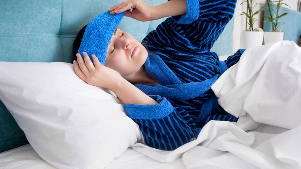 Portrait of sick woman after hangout suffering from headache putting cold wet towel on forehead — Stock Photo, Image