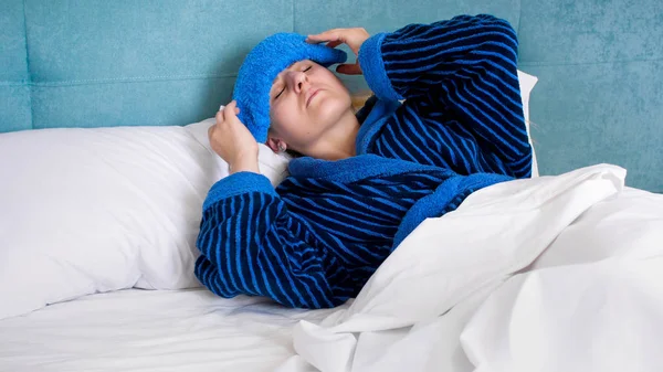 Photo of sick woman suffering from head ache putting wet compress on forehead — Stock Photo, Image