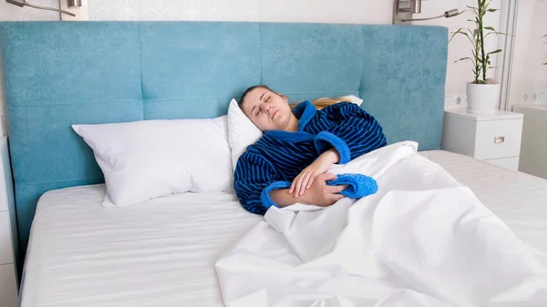Foto mladá nemocná žena v županu, spí v posteli — Stock fotografie