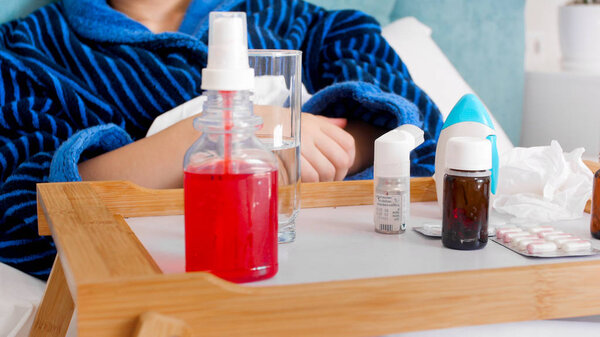 Closeup image of lots of different medicines, pills and spray on tray in bed