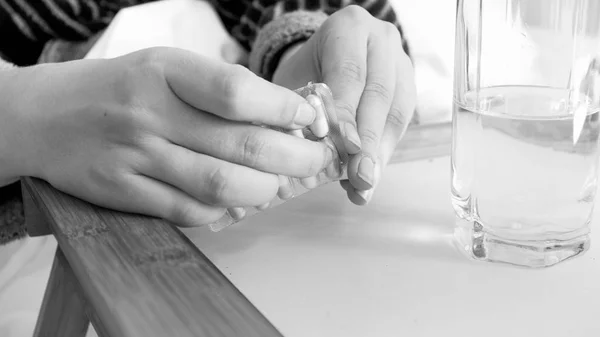 Image en noir et blanc des mains féminines déballant les pilules — Photo