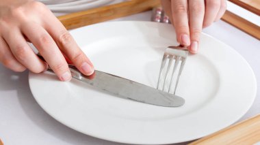 Diyet ve kilo verme kavramı. Yemek masası üzerinde boş levha üzerine çatal ve bıçak tutan eller