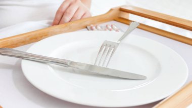 Portre resim hapları ve boş tabak hasta kadın yatakta ahşap tepsi üzerinde. Diyet ve kilo verme kavramı