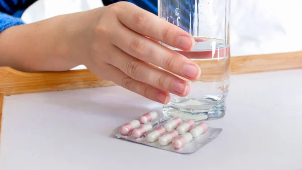 Closeup image of sick woman holding glass of water to drink pills — Stock Photo, Image