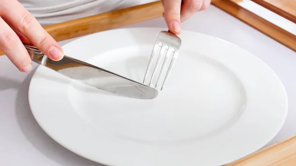 Närbild bild av kvinnliga händer håller gaffel och kniv på tomma skålen. Begreppet kost och banta — Stockfoto