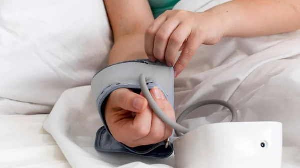Foto di primo piano della donna che si sente male mettendo il monitor digitale della pressione sanguigna sul braccio — Foto Stock