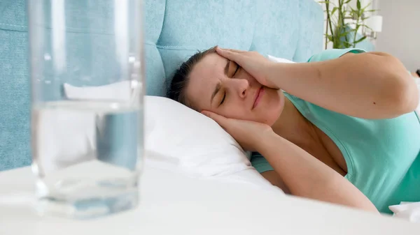 Retrato de cerca de la mujer enferma con dolor de cabeza después de la resaca acostada en la cama — Foto de Stock