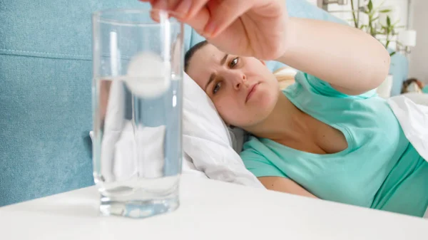 Portrét mladé ženy pocit nevolnosti vrhací prášek ve sklenici vody — Stock fotografie