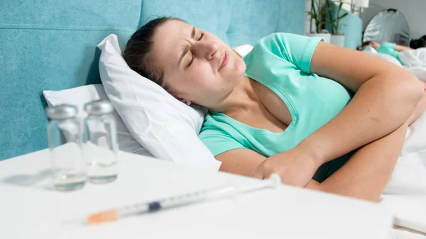 รูปภาพของหญิงสาวที่ติดยา นอนอยู่บนเตียง และทุกข์ทรมานจากความเจ็บปวด — ภาพถ่ายสต็อก