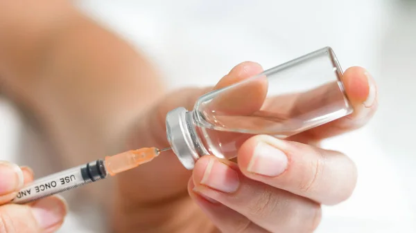 Macro image of female doctors hands holding ampule with medication and filling syringe — Stock Photo, Image