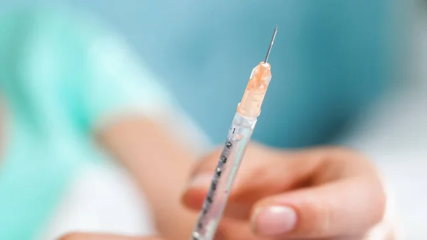 Närbild bild av vassa nålen på sprutan i kvinnlig hand — Stockfoto