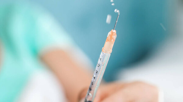 Macro image of nurse releasing air bubbles from syringe with medictaion for injection