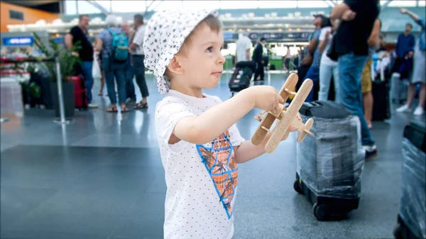Портрет двухлетнего мальчика, играющего с игрушечным самолетом в аэропорту — стоковое фото