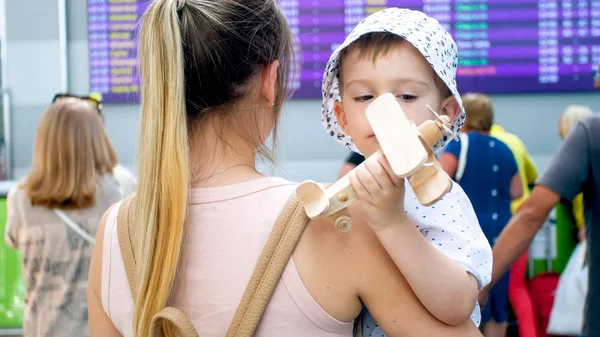 Retrato de menino bonito brincando com avião de brinquedo e jovem mãe no terminal do aeroporto internacional — Fotografia de Stock