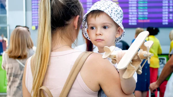 Portrait de mignon tout-petit garçon avec jeune mère debout au grand moniteur avec l'heure de départ de l'avion — Photo