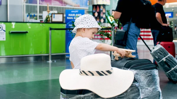Тоноване зображення маленького хлопчика, який чекає на політ і грає з іграшковим літаком — стокове фото