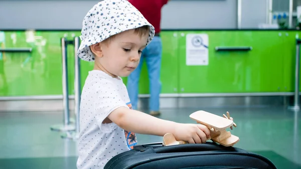 Portrait de petit garçon tout-petit avec jouet avion en bois dans l'aéroport international — Photo