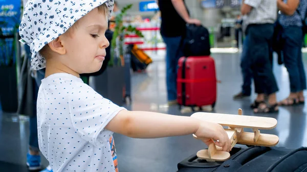 Porträtt av lilla pojke leker med leksak flygplan och stora resväska — Stockfoto