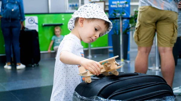 Porträtt av liten toddler pojke leker med trä flygplan väntan på flyg i flygplats — Stockfoto