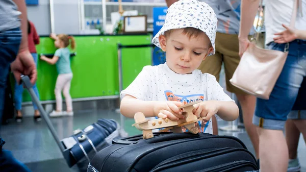 Portrait de petit garçon concentré jouant avec un avion miniature en bois dans le terminal de l'aéroport — Photo