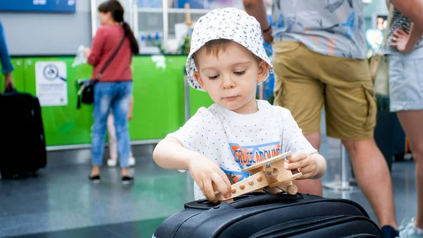 Portrait rapproché d'un petit garçon tenant et jouant avec un avion miniature en bois. Enfant voyageant. Jeunes touristes . — Photo
