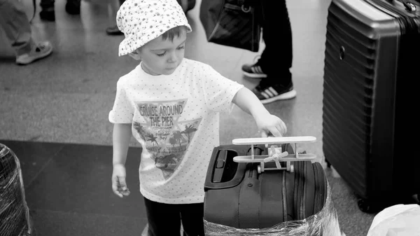 Black and white image of little toddler boy with toy airplane playing in airport terminal. Child traveling. Young tourist. — Stock Photo, Image