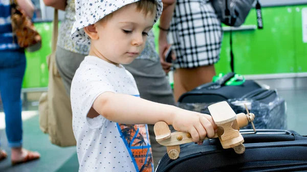 Portrait d'un petit garçon jouant avec un avion jouet avant le premier vol. Enfant voyageant. Jeunes touristes . — Photo