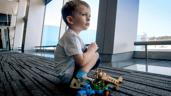 Портрет грустного мальчика, сидящего на полу в терминале аэропорта — стоковое фото
