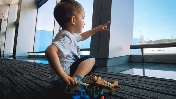 空港に飛行機が大きな窓を通して見る興奮して幼児男の子の肖像画 — ストック写真