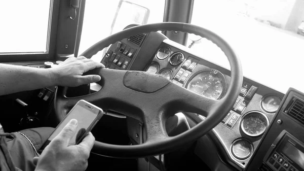 Black and white image of bus driver using smartphone while driving — Stock Photo, Image