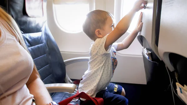 Kleiner 2-jähriger Junge spielt mit Klapptisch im Flugzeug — Stockfoto