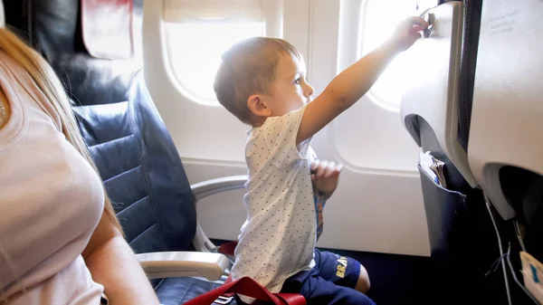 Portrait of little boy locking foldable table on seat at passenger aircraft — Stock Photo, Image