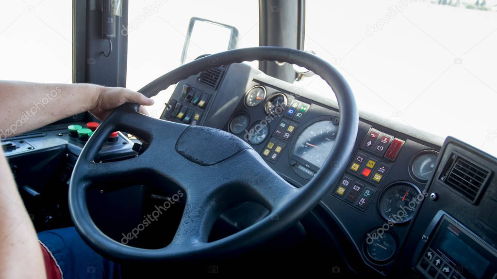Closeup photo of male hands on steering wheel while driving public bus