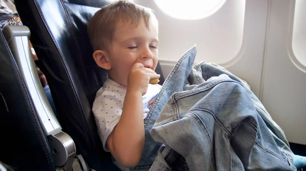 Retrato de niño divertido comiendo durante el vuelo en avión — Foto de Stock