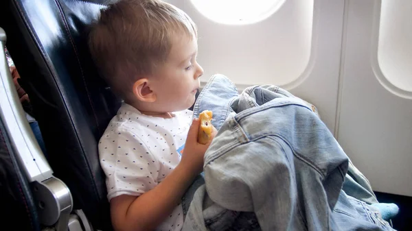 Retrato del niño comiendo bocadillos durante el primer vuelo en avión — Foto de Stock