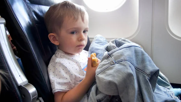 Retrato tonificado de un lindo niño comiendo durante el vuelo en avión — Foto de Stock