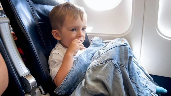 Pequeño niño sentado en el asiento del avión y merienda — Foto de Stock