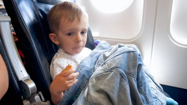 Retrato de lindo niño cubriendo en jascket sentado en el asiento del pasajero del avión — Foto de Stock
